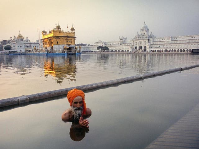 Amritsar, Indië:
A Sikh pilgrim 
performs his ritual 
washing in the 
lake 
with the most 
famous place of 
worship for the 
Sikhs in the 
background. 