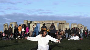 A reveler prays at sunrise as thousands gather at the ancient stone circle Stonehenge to celebrate the Summer Solstice on June 21