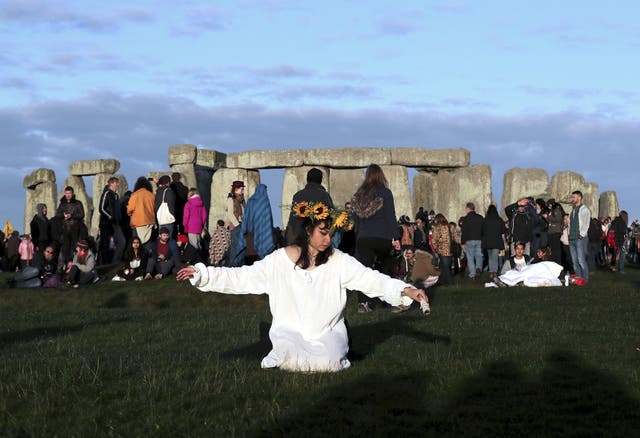 A reveler prays at sunrise as thousands gather at the ancient stone circle Stonehenge to celebrate the Summer Solstice on June 21