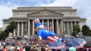 People watch the Independence Day parade as it passes in front of the National Archives