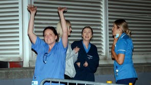 Staff outside the St James's University Hospital in Leeds, wave to people applauding them from their balconies