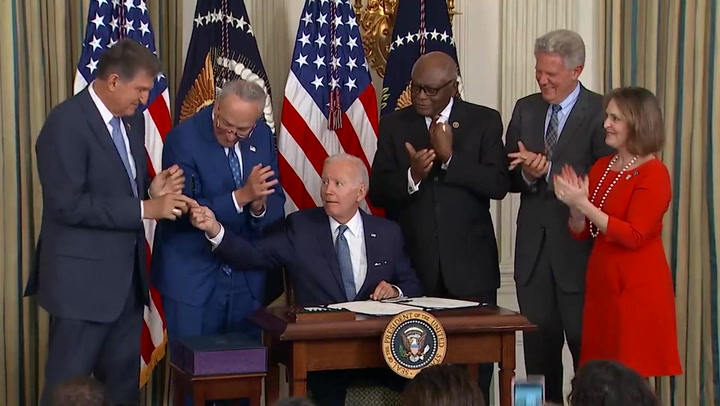 Joe Biden hands Senator Joe Manchin pen after signing Inflation Reduction Act into law