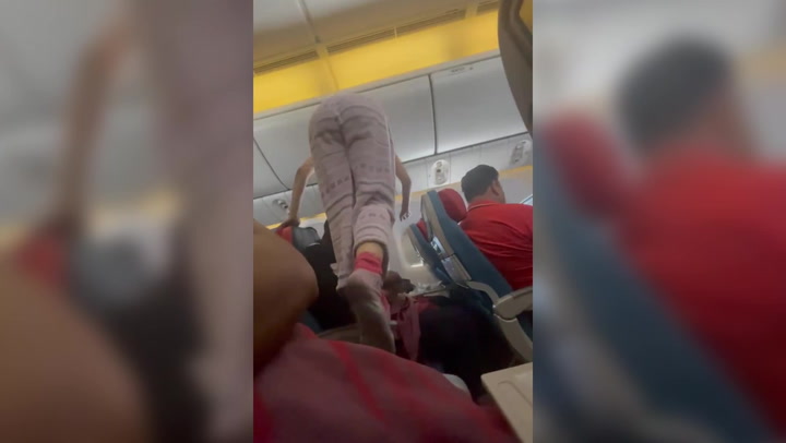 Woman climbs over row of passengers to return to seat during flight