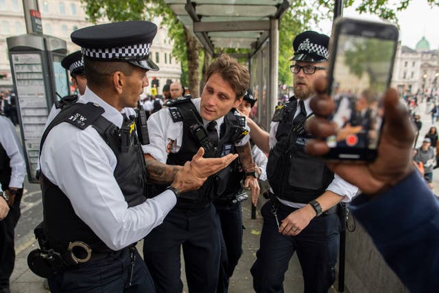 An injured police officer is assisted by his colleagues during a protest in London