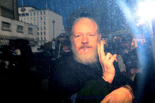 Julian Assange gestures to the press from a police vehicle on his arrival at Westminster Magistrates’ Court on 11 April, 2019