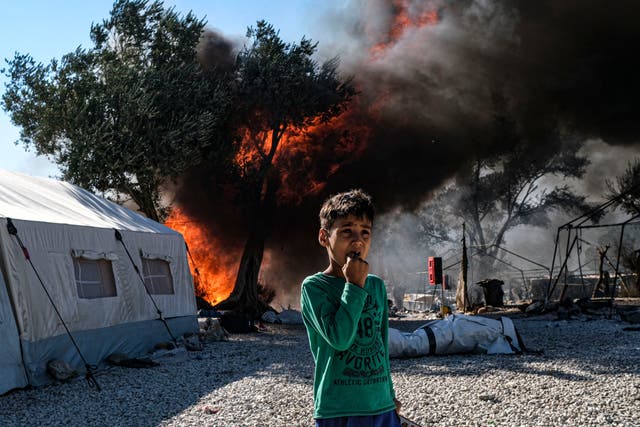An Afghan asylum-seeking boy looks on as fires which started on Tuesday night continue to rage into Thursday morning inside of Moria camp