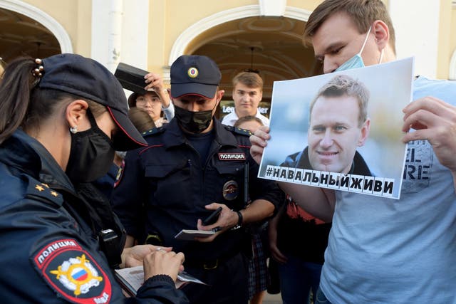 A supporter of Navalny has his documents checked by police in the wake of his hospitalisation