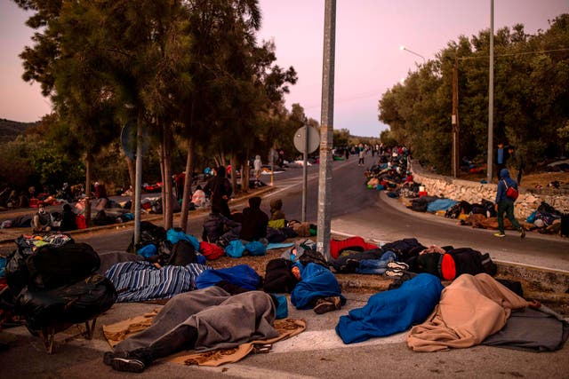Migrants sleep by the road  after a fire destroyed Greece's largest Moria refugee camp on the island of Lesbos on September 10, 2020