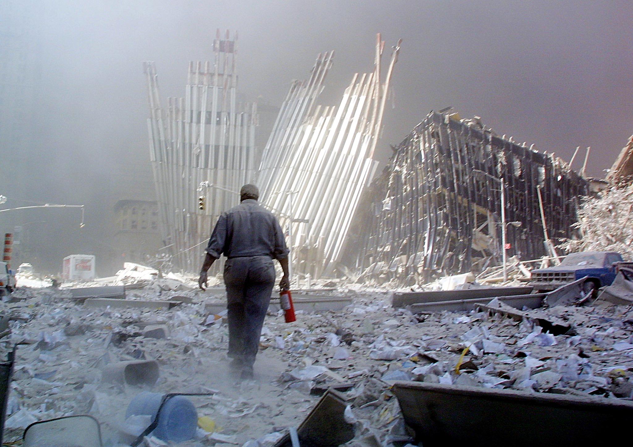 A man with a fire extinguisher walks through rubble after the collapse of the first World Trade Centre Tower 11 September, 2001