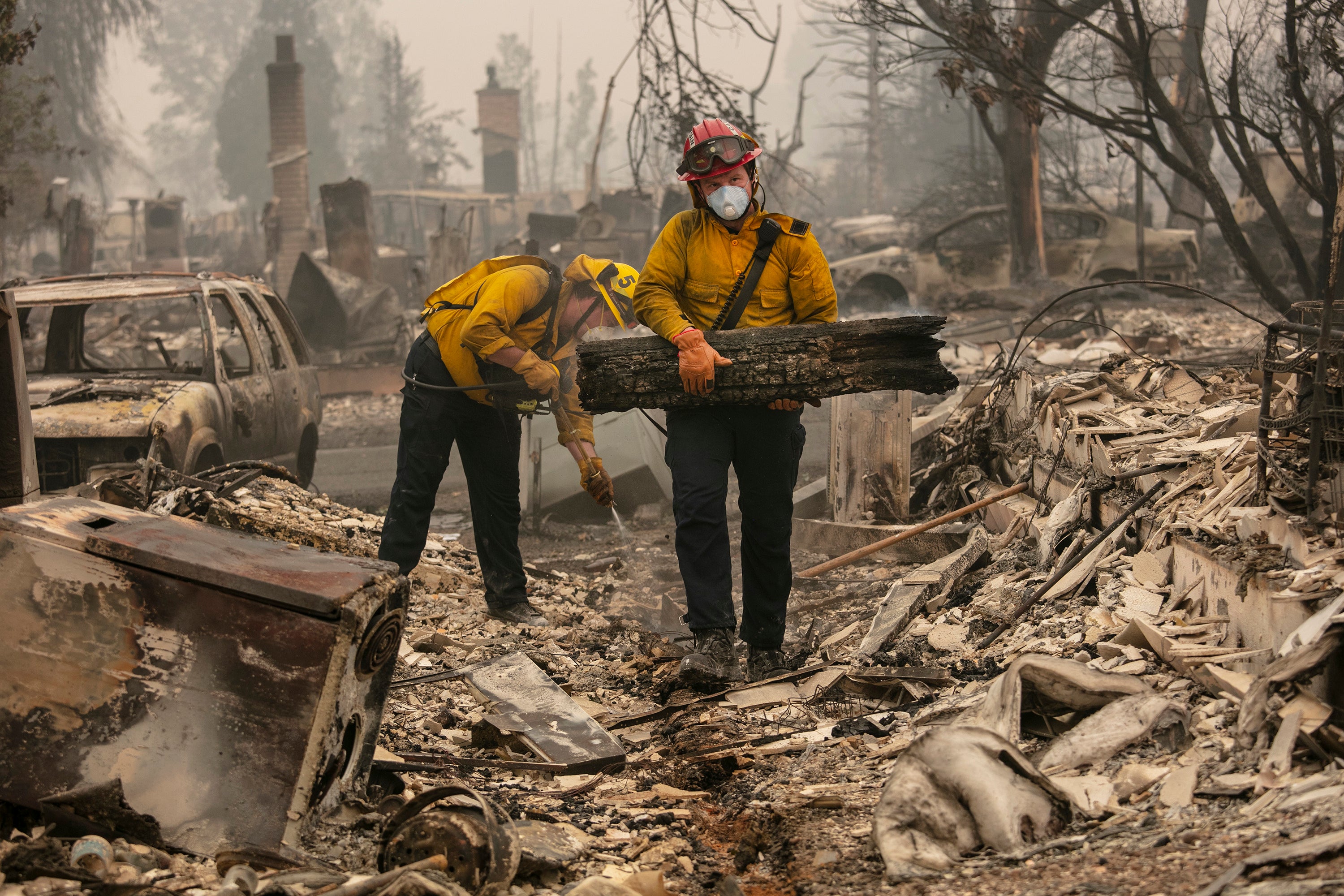 Jackson County District 5 firefighter Captain Aaron Bustard, right, and Andy Buckingham work on a smouldering fire in a burned neighbourhood as destructive wildfires devastate the region on Friday