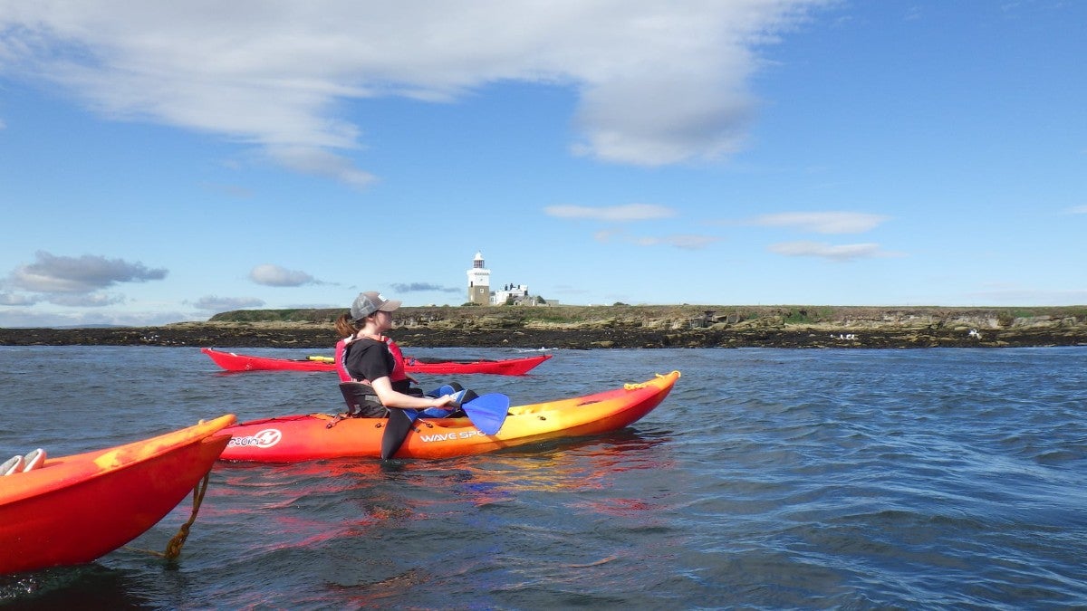 Kayakers paddle past the island in calmer waters