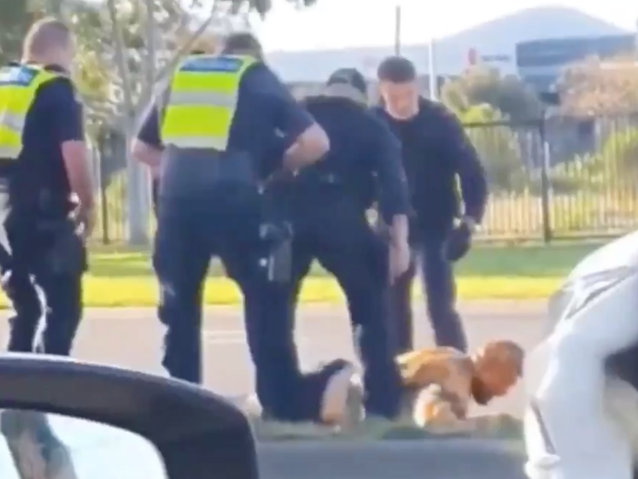 Victoria Police officers surround a man on the ground after hitting him with a police car