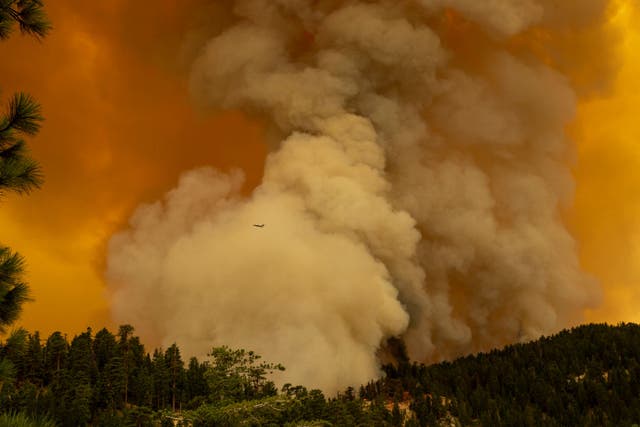 An air attack plane flies by the plume as the Bobcat Fire advances in the Angeles National Forest 