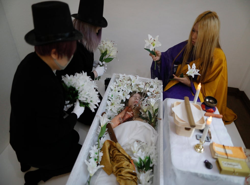 Makeup artist Hiiro, Leiya Arata and Lay Kato place flowers next to the body of a Japanese man Mako playing dead