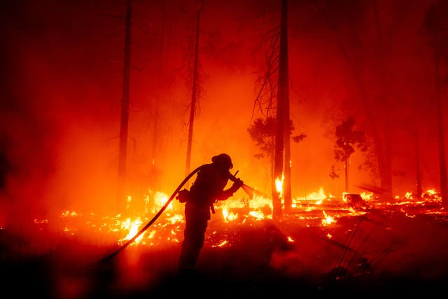 A firefighter battles the Creek Fire as it threatens homes in the Cascadel Woods neighborhood of Madera County, Calif
