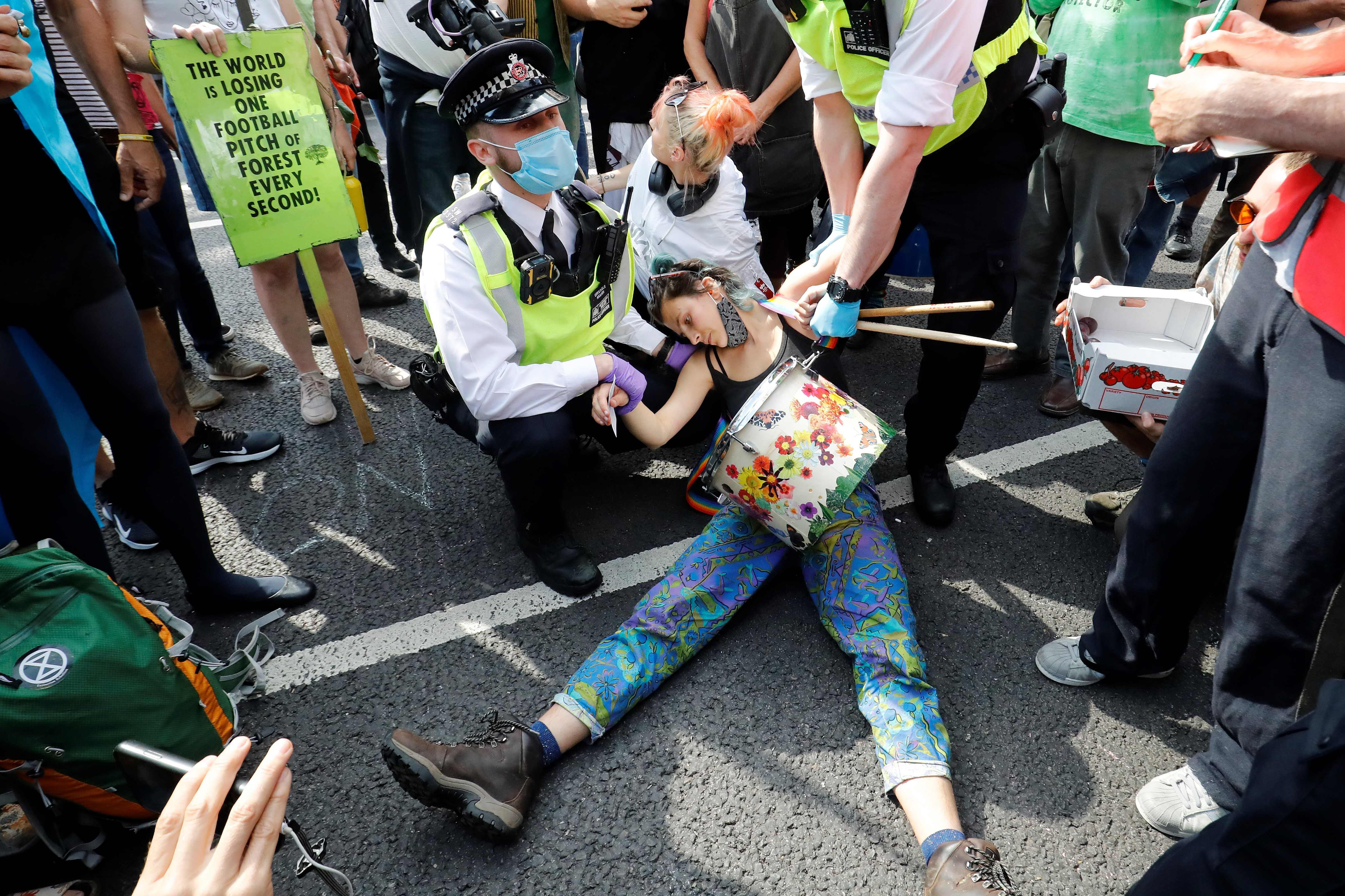 Police officers wearing face masks and gloves due to the COVID-19 pandemic, detain an activist from the climate protest group Extinction Rebellion as they demonstrate in Parliament Square in London on September 2, 2020, on the second day of their latest season of "mass rebellions"