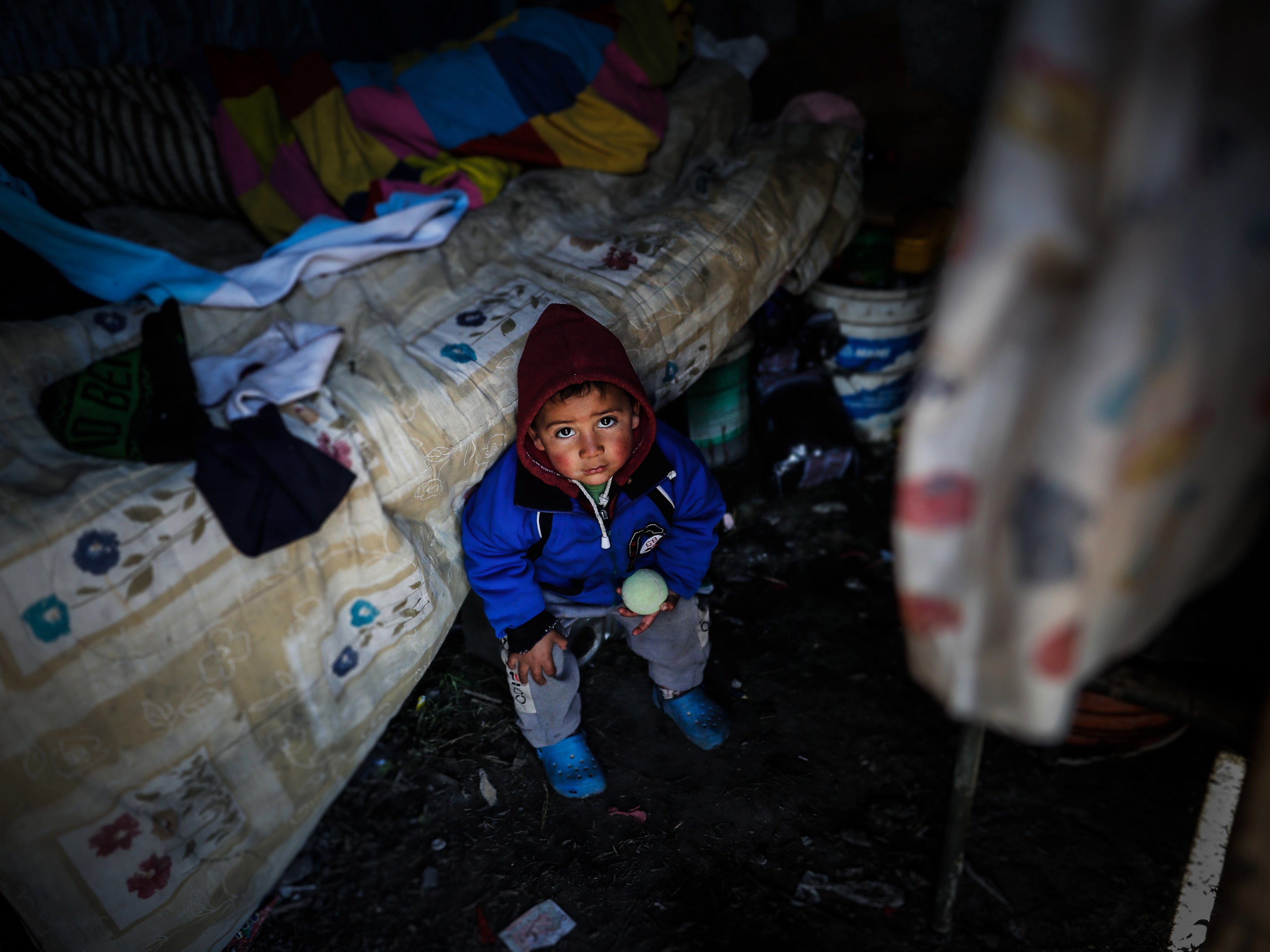 A child sits inside a home on a piece of land in the town of Guernica, 30 km from the City of Buenos Aires, Argentina