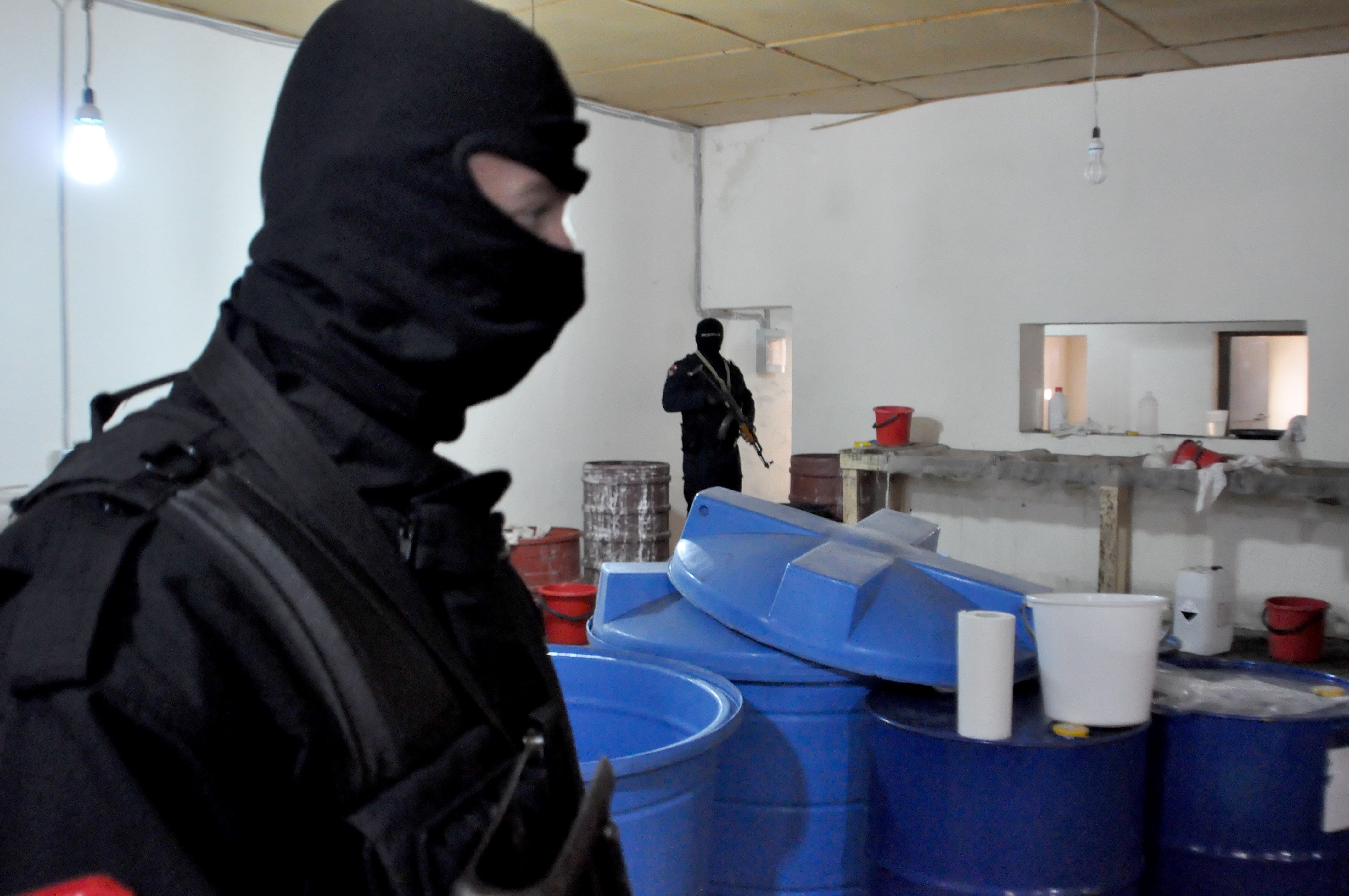 Albanian police officers search a clandestine cocaine refining laboratory