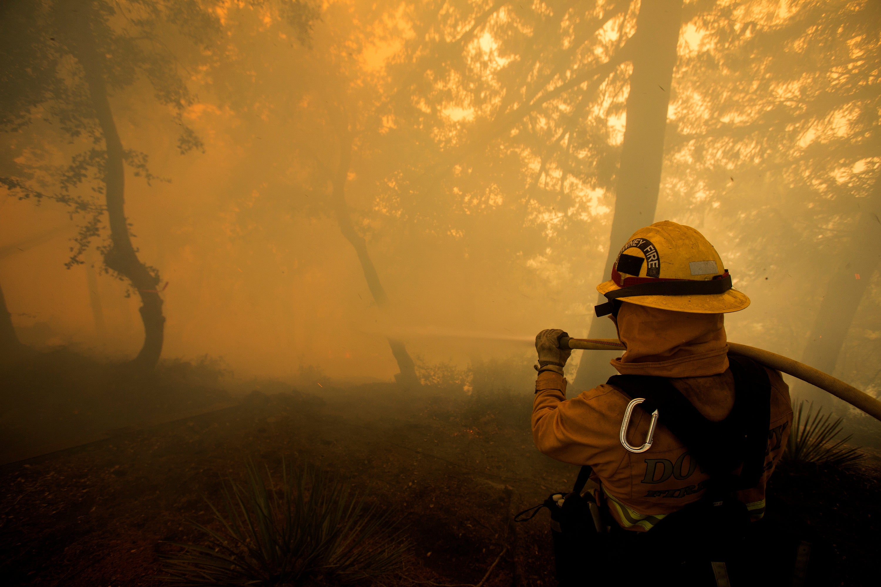 A firefighter battles a wildfire near a structure while defending the Mount Wilson observatory