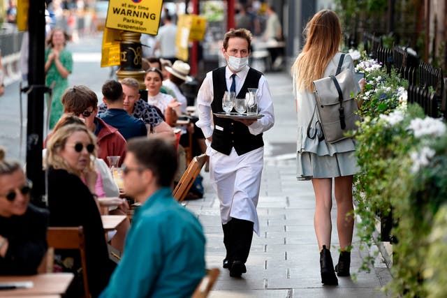 A waiter wears a face mask while serving customers at a restuarant in Soho, London, 20 September 2020