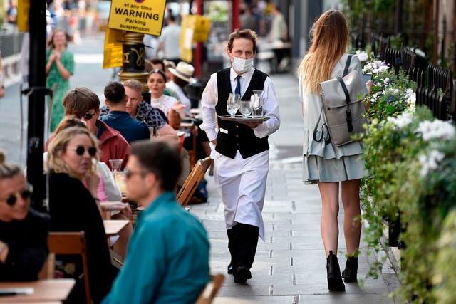A waiter wears a face mask while serving customers at a restuarant in Soho, London, 20 September 2020