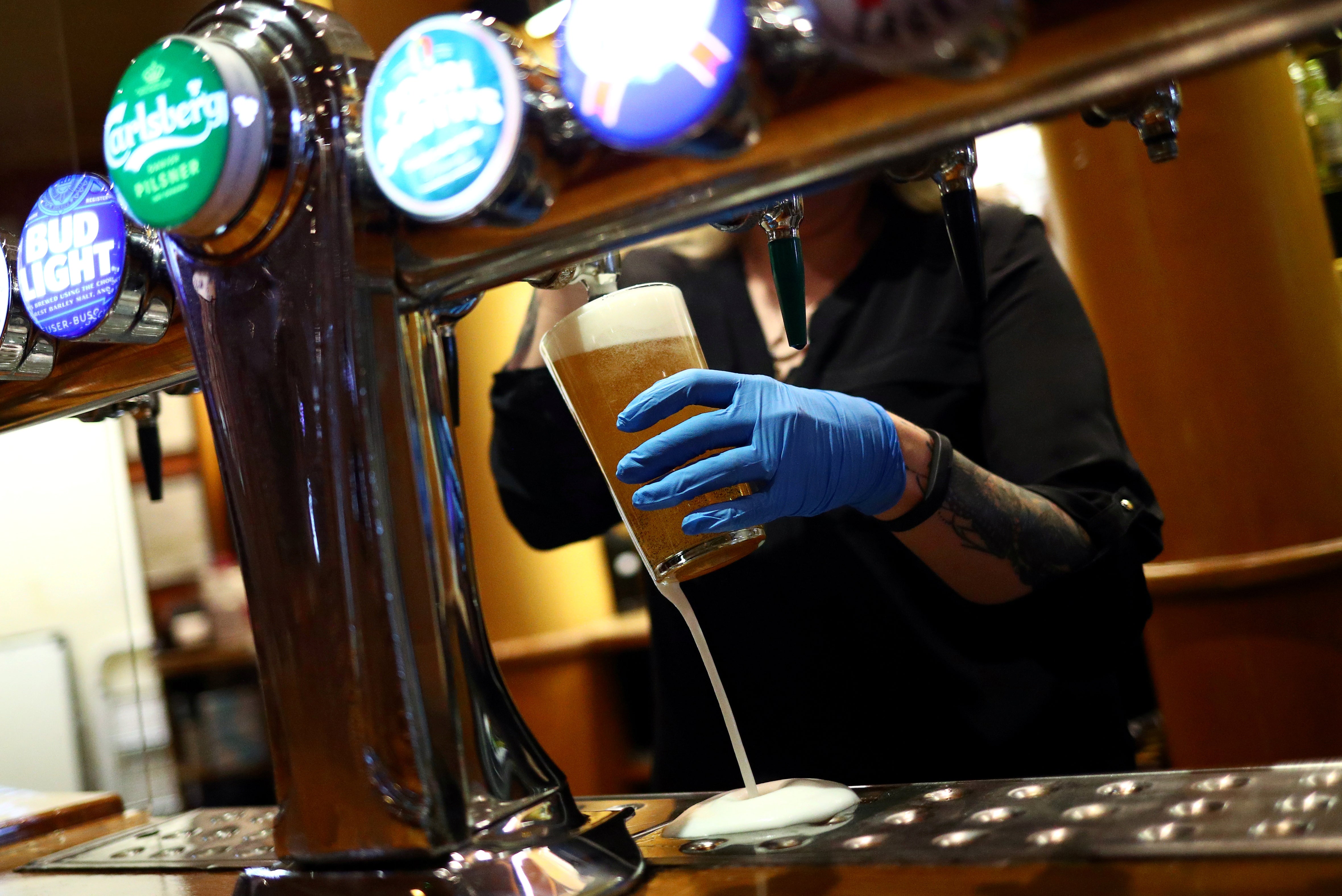 A worker serves a beer at The Holland Tringham Wetherspoons pub in London