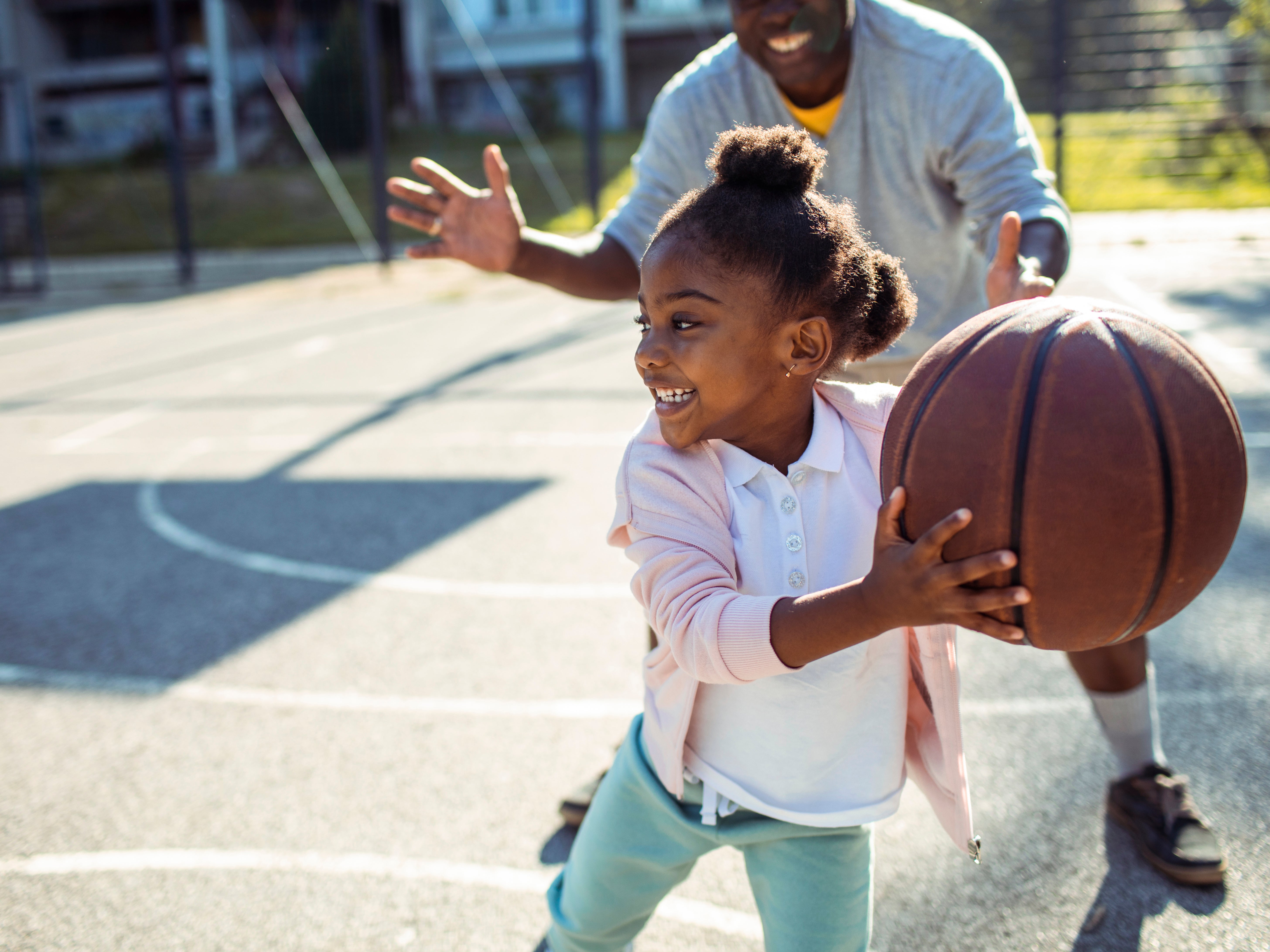A father plays basketball with his young daughter