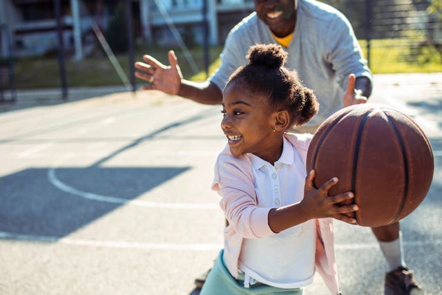 <p>A father plays basketball with his young daughter</p>