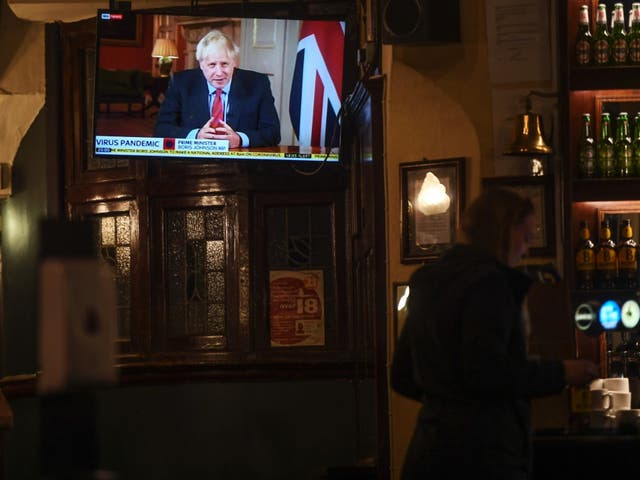 People watch Boris Johnson making a televised address to the nation inside the Westminster Arms pub on Tuesday evening