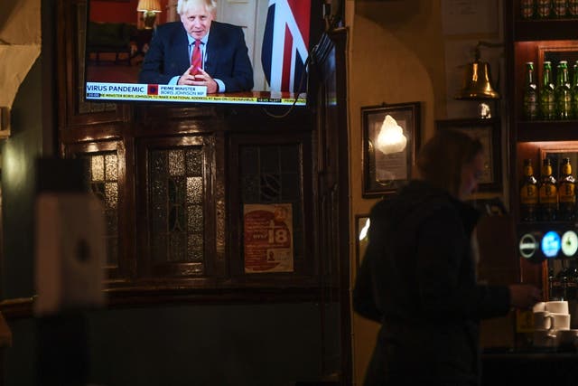 People watch Boris Johnson making a televised address to the nation inside the Westminster Arms pub on Tuesday evening