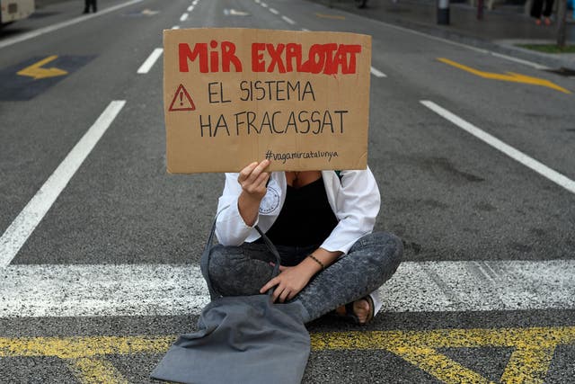 A Medical Resident in Barcelona holds a placard reading "Exploited Medical Resident, the system failed" during a protest against working conditions amid a surge in Spanish cases