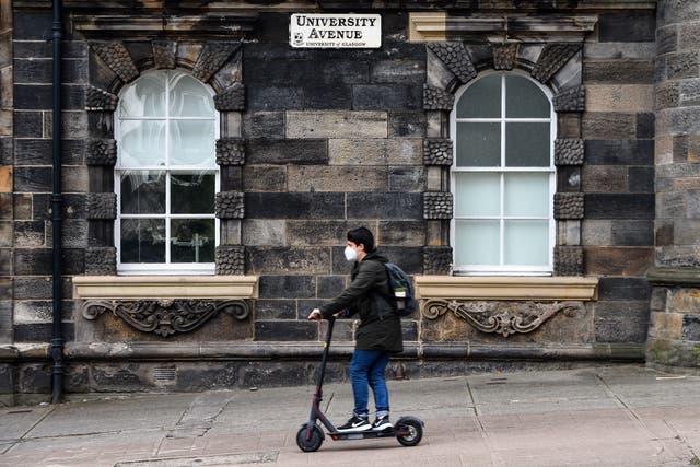 A student wearing a face mask passes through the University of Glasgow campus