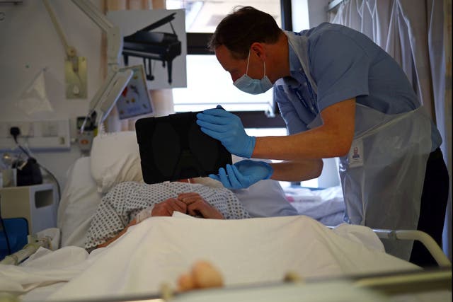 A patient communicates with family on an iPad held by a member of NHS staff