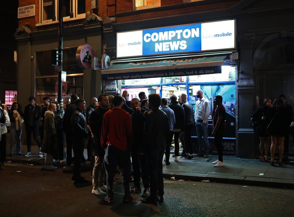 People queue for a convenience store in Soho, London, after pubs and restaurants were subjected to a curfew at 10 p.m.