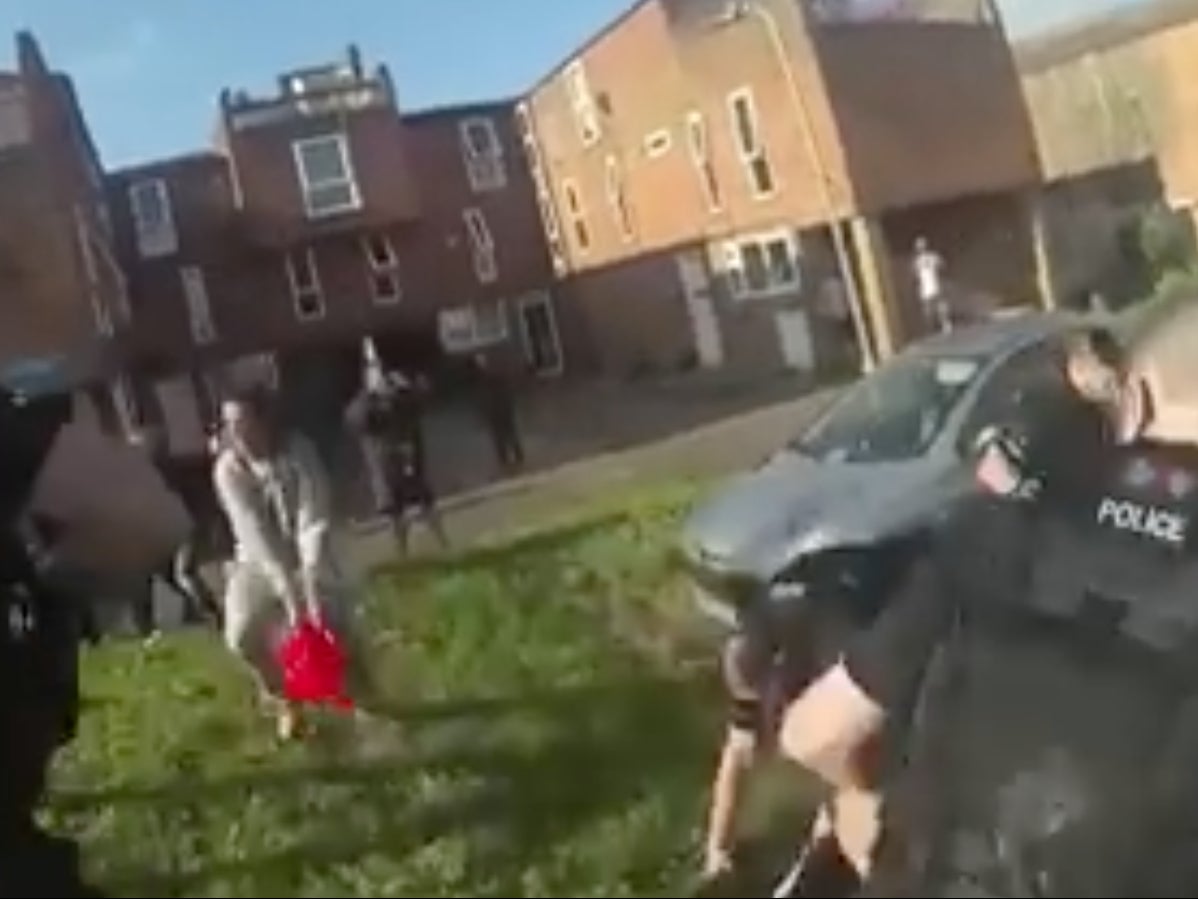 A still from video footage of the incident shows police ducking as Justin Jackson throws petrol at them out of a red watering can 