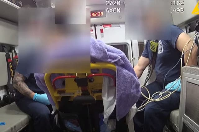 A still from bodycom footage shows the patient in a gurney and Andrew Cruikshank (accused) on the right