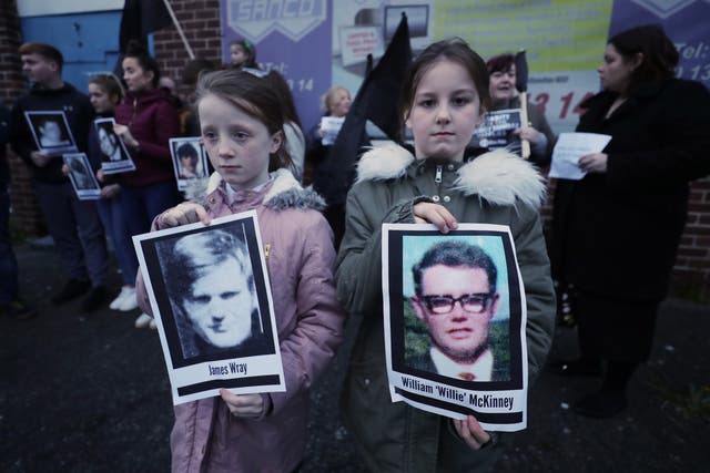 Two children hold pictures of Bloody Sunday victims James Wray and William McKinney during a vigil in West Belfast