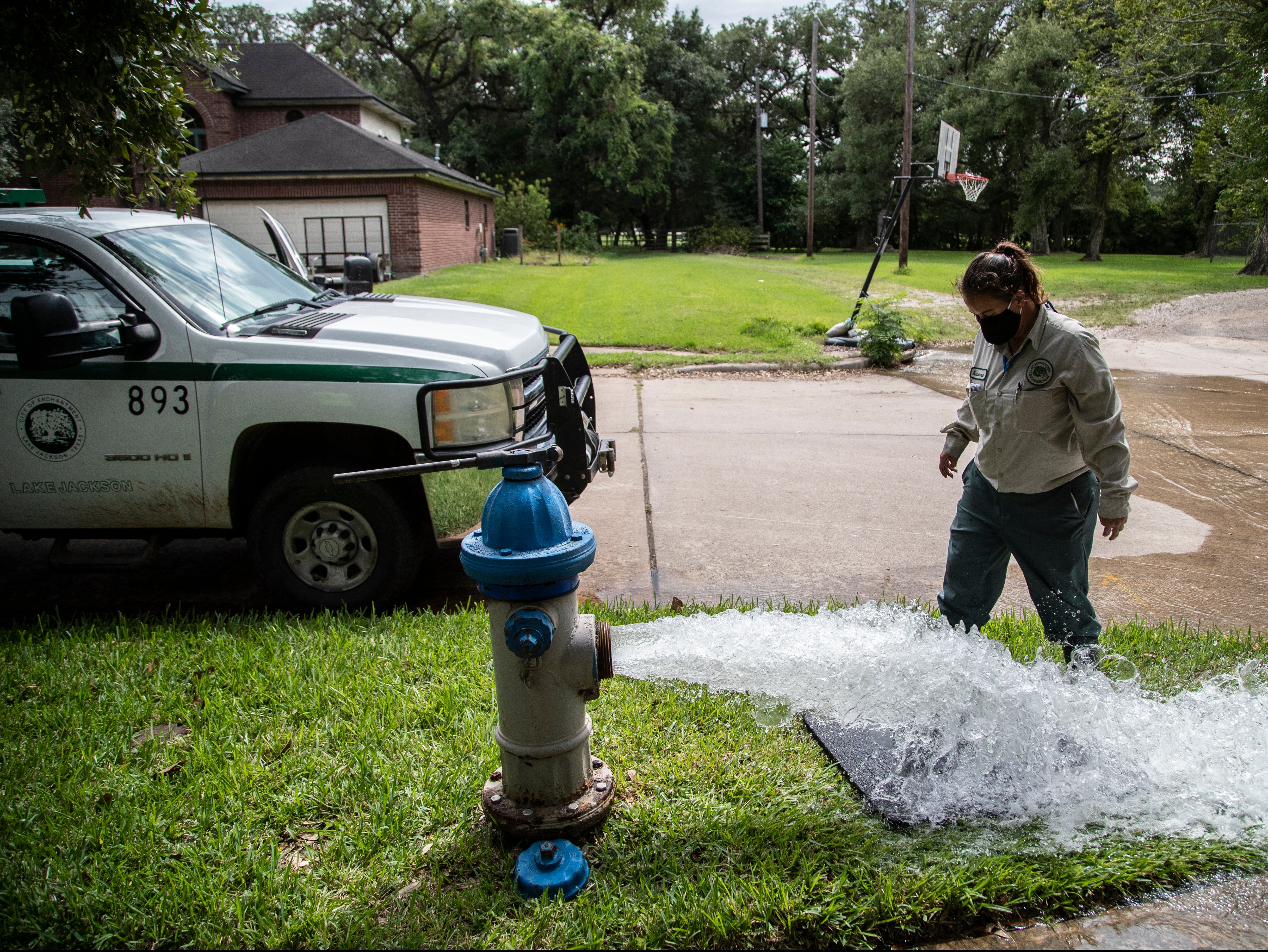 A Lake Jackson water waste operator flushes water out from a fire hydrant