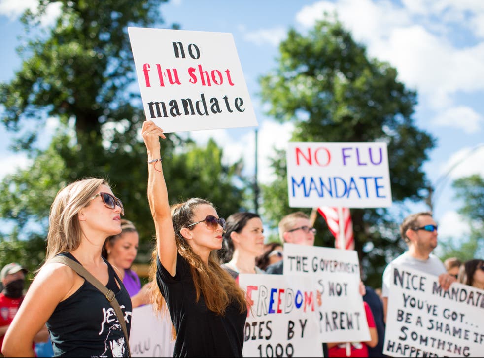 Anti-vaccine activists hold signs in front of the Massachusetts State House during a protest against mandatory vaccines