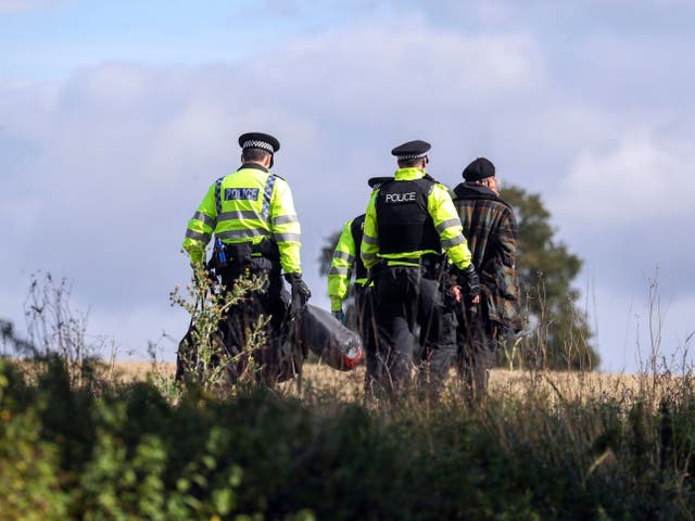 A protester is escorted off a HS2 construction site by police at Jones' Hill Wood in Buckinghamshire