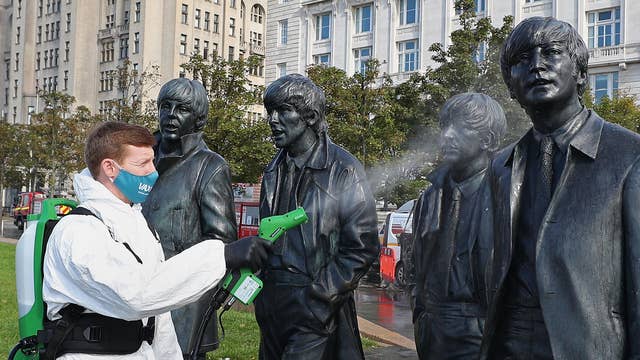 A worker spray cleans the Beatles statue in Liverpool