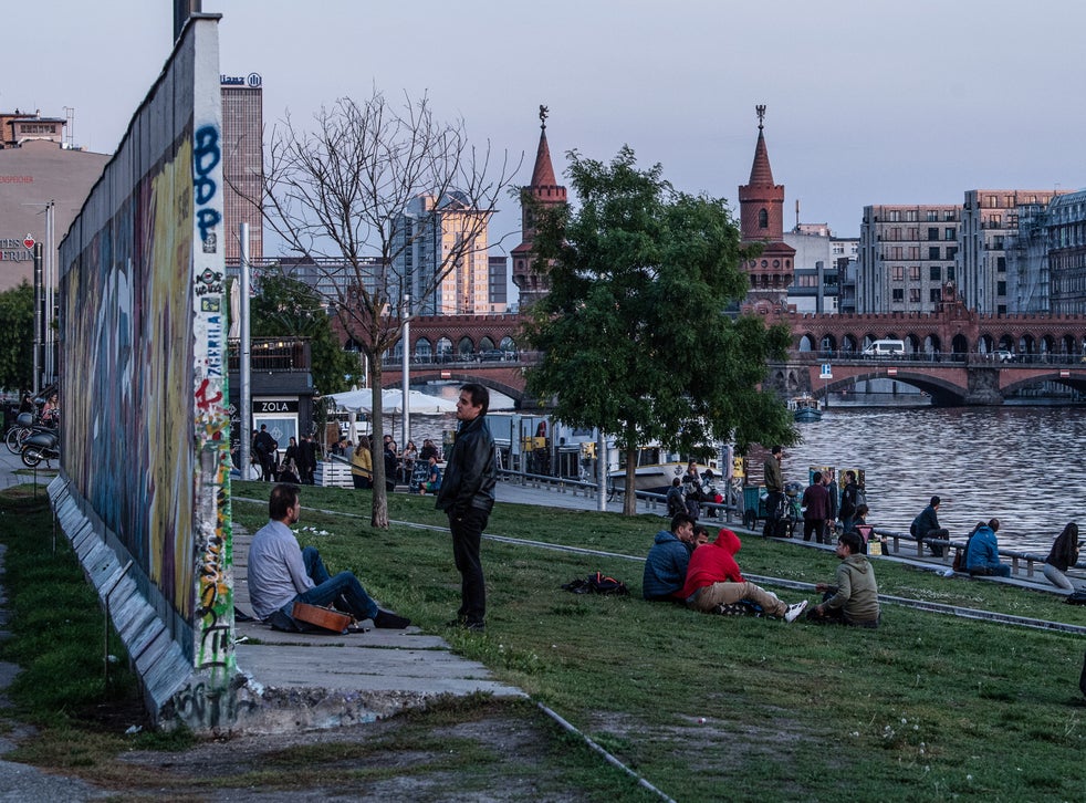 Visitors next to a remaining section of the Berlin Wall at the East Side Gallery