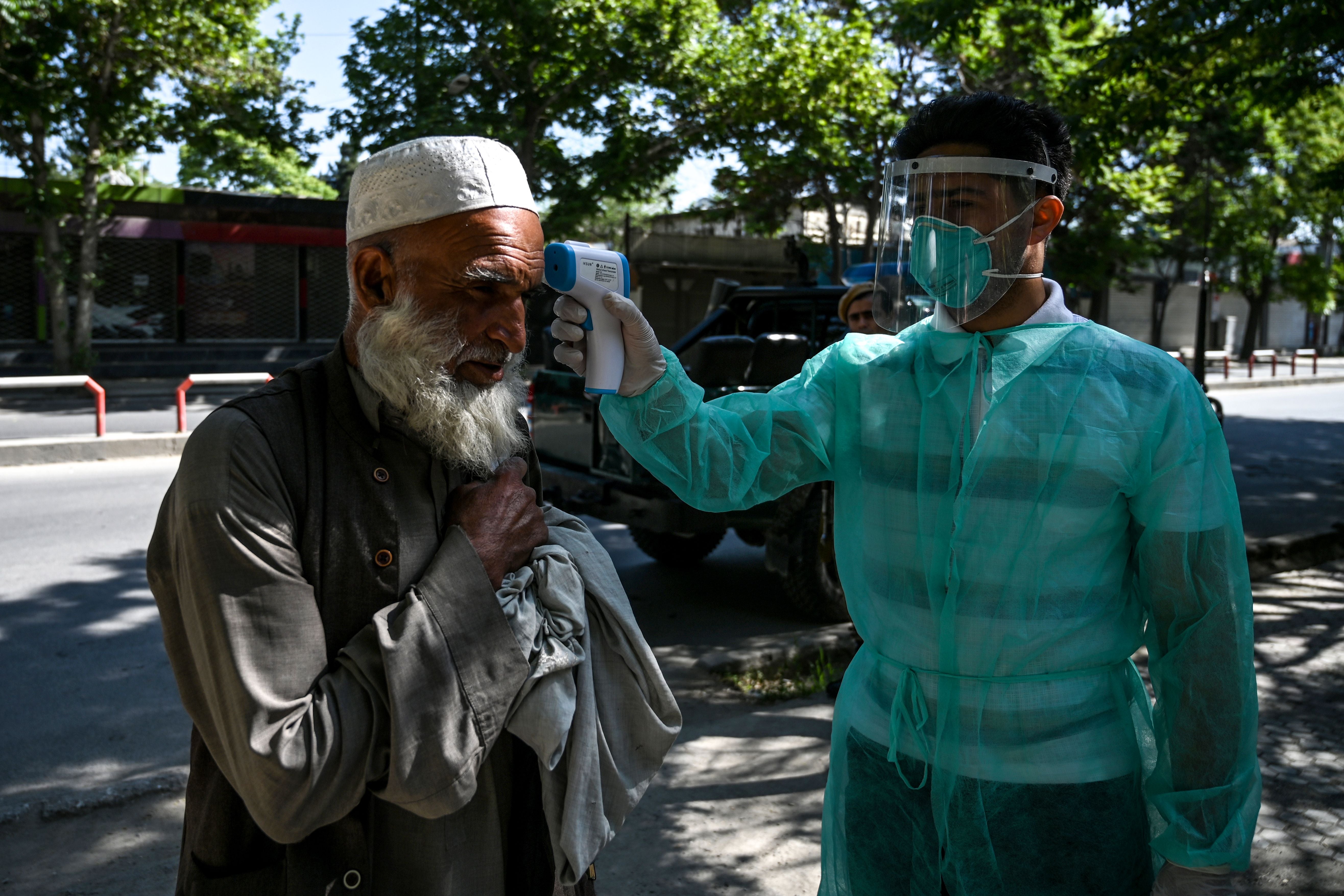 A health worker checks the body temperature of a man in Kabul, Afghanistan