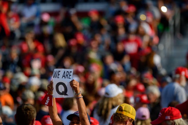A woman holds up a QAnon sign to the media as attendees wait for President Donald Trump to speak at a campaign rally