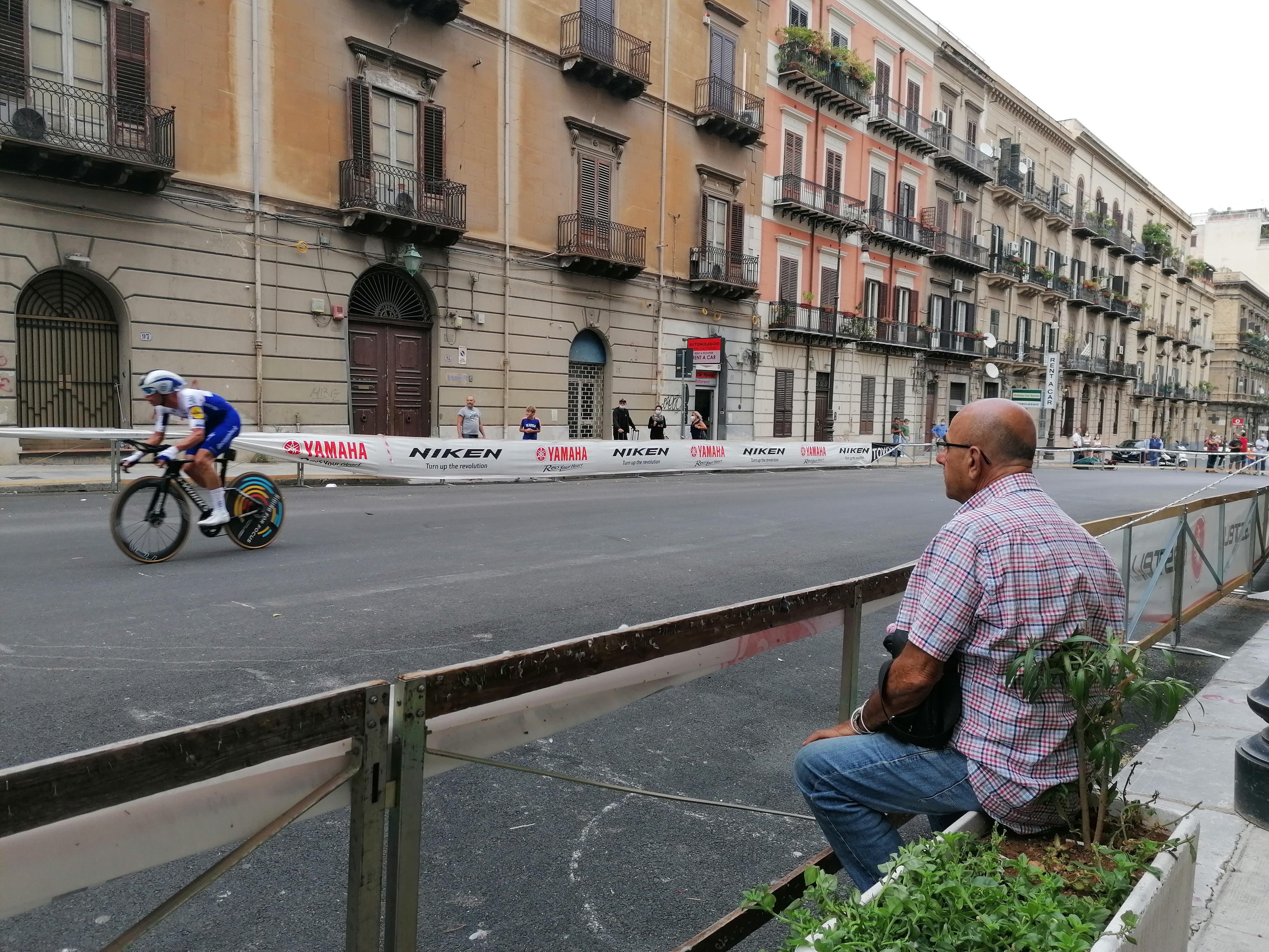 A man sits and watches the riders roar past on Stage 1 of the Giro d’Italia 2020