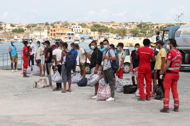 Migrants wait to board a coast guard ship off Lampedusa island