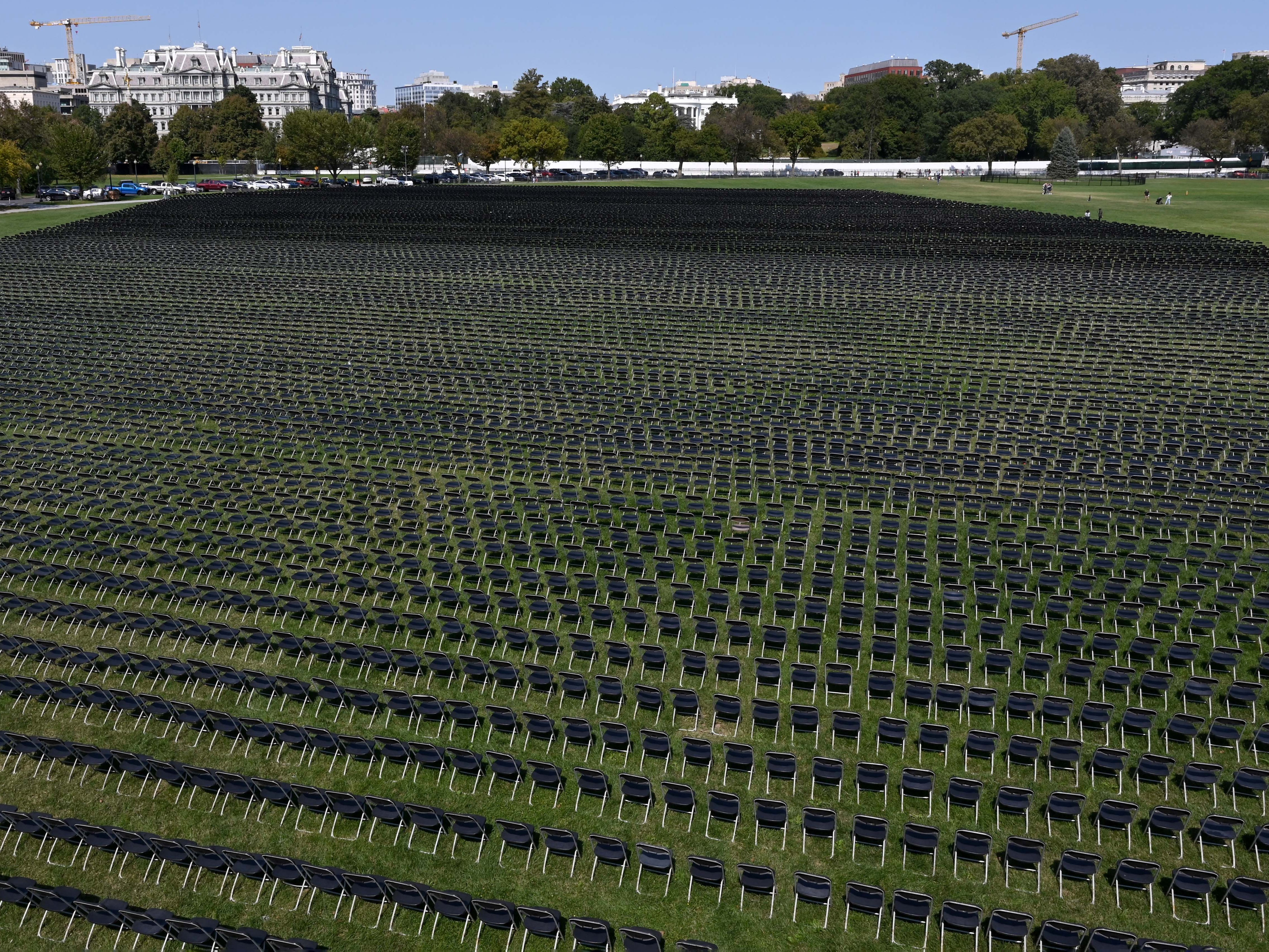 With the White House in the background, 20,000 chairs, each representing 10 deaths from the coronavirus pandemic in the US are lined up on the Ellipse for a remembrance event Sunday