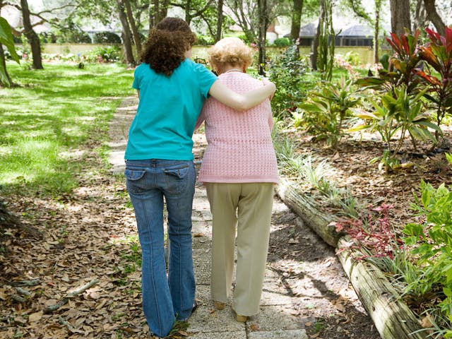 Granddaughter helps her grandmother, who has dementia, to walk with the aid of a walker