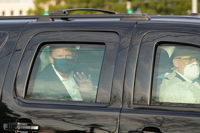 US president Trump waves from the back of a car in a motorcade outside of Walter Reed Medical Centre in Bethesda, Maryland on 4 October 2020