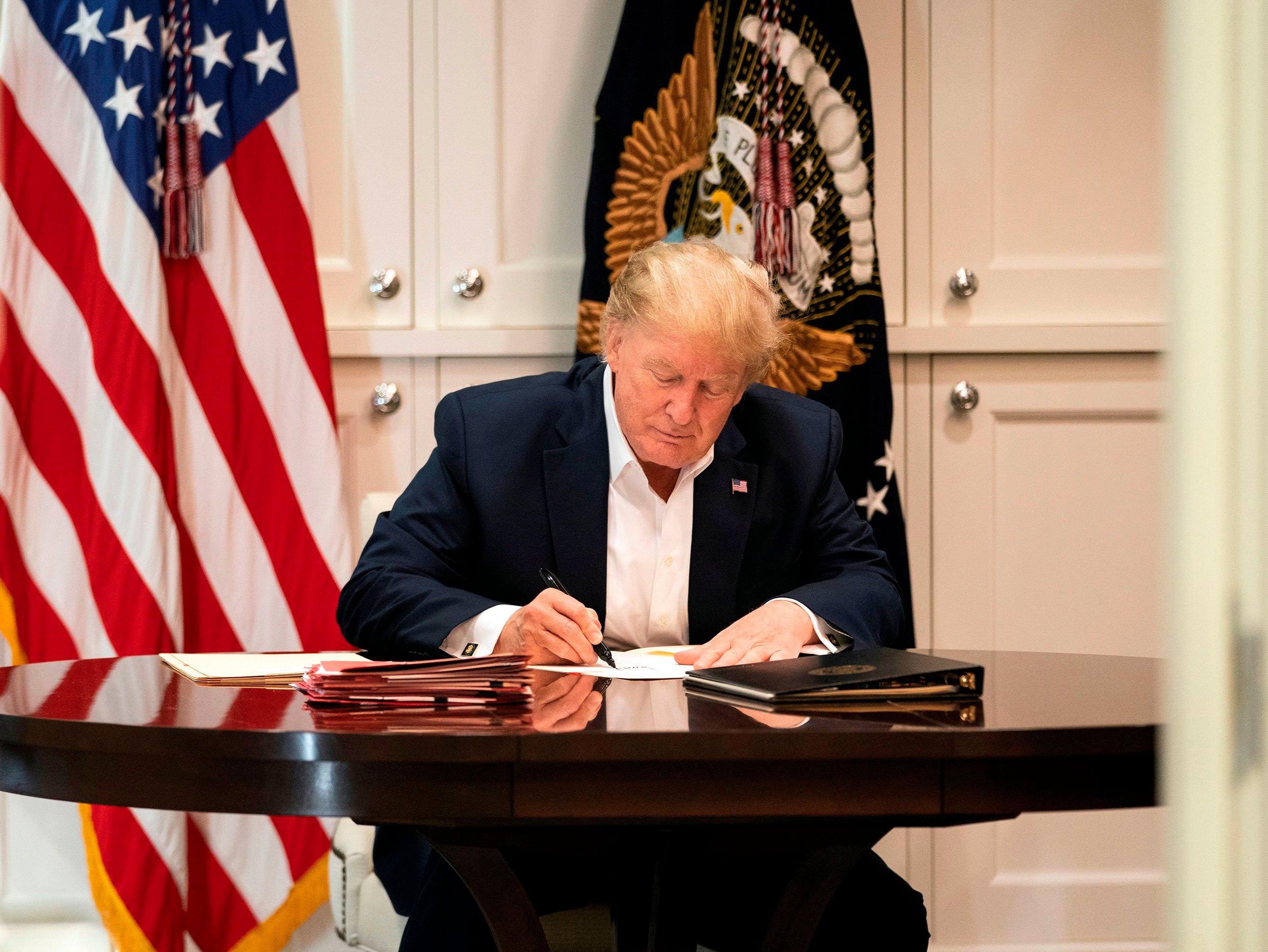 This White House handout photo released 4 October 2020 shows US president Donald Trump working in the Presidential Suite at Walter Reed National Military Medical Centre in Bethesda, Maryland on 3 October 2020, after testing positive for Covid-19
